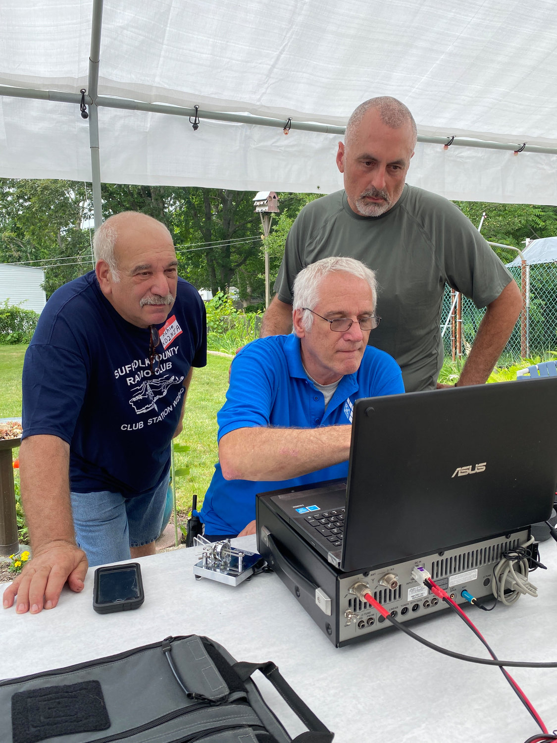 During a recent Amateur Radio Field Day in Shirley (left to right), Richie Geraci, Pres Waterman and Ed Wilson attempt to communicate with other radio clubs using Morse code. Waterman can communicate at 30 words per minute, considered “fast Morse.”